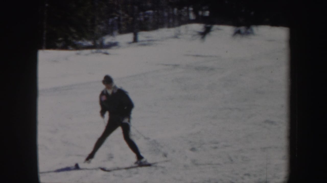 Adult skier crosses the snowy Vermont slope with poles, framed by dark woods in 1962 home-movie footage.
