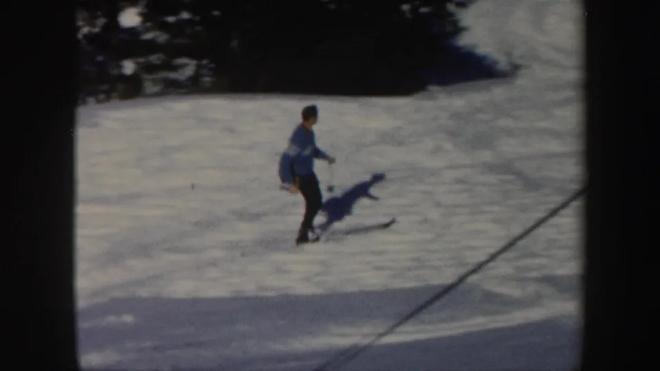 The skier appears farther away on the snowy Vermont slope, framed by dark film edges and trees in the background.