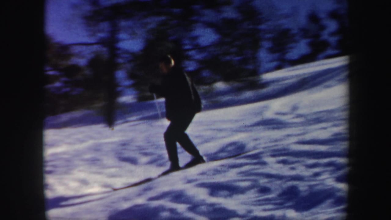 1962 Vermont home-movie frame of a skier traversing a snowy hillside, with dark trees and visible 8mm film borders.