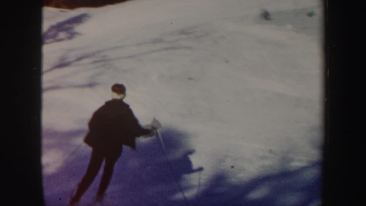 In 1962 Vermont home-movie footage, a dark-clad skier descends a snowy slope in strong sunlight.
