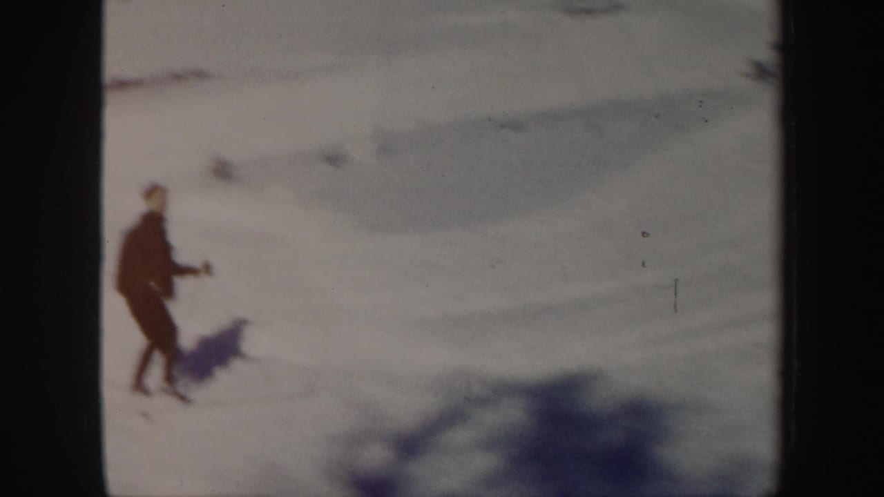 A distant skier in dark clothing moves over bright snow in Vermont winter footage from 1962.