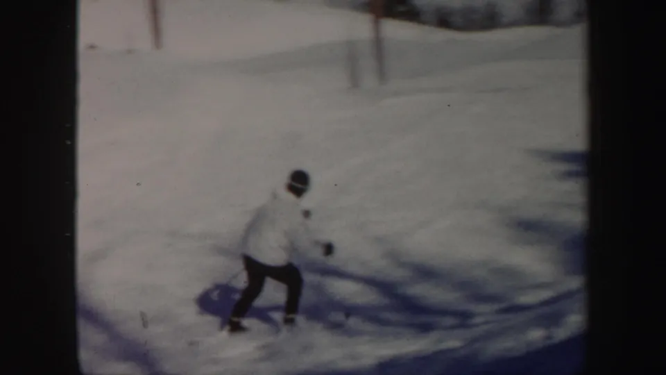 A light-jacketed skier descends a sunlit Vermont slope in soft, grainy 1962 8mm footage.