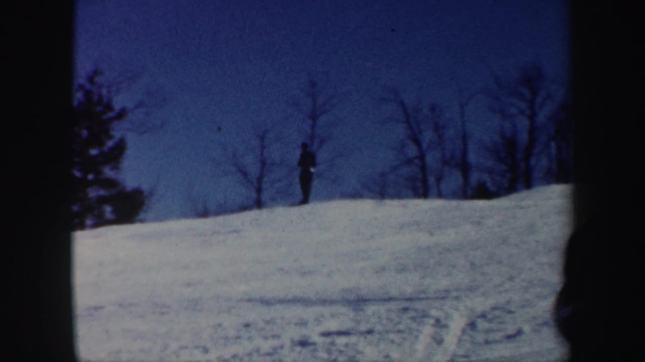 Distant skier silhouetted near the ridge of a Vermont snow slope in soft 1962 home-movie footage.