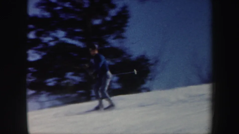1962 Vermont 8mm frame showing a skier in dark clothing descending a snowy slope with poles in hand.