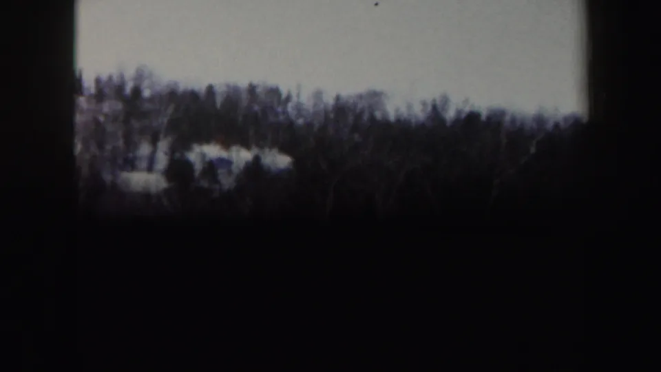 A Vermont 1962 home-movie frame shows a snowy slope and distant treeline before the skiers are clearly centered.