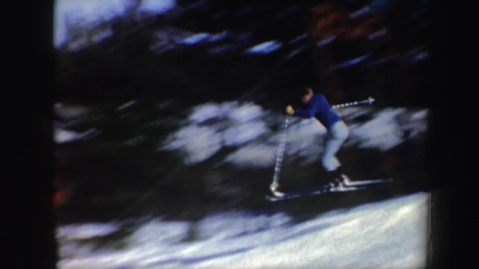 Closer 8mm frame of the skier leaning forward at speed on a snowy Vermont slope.