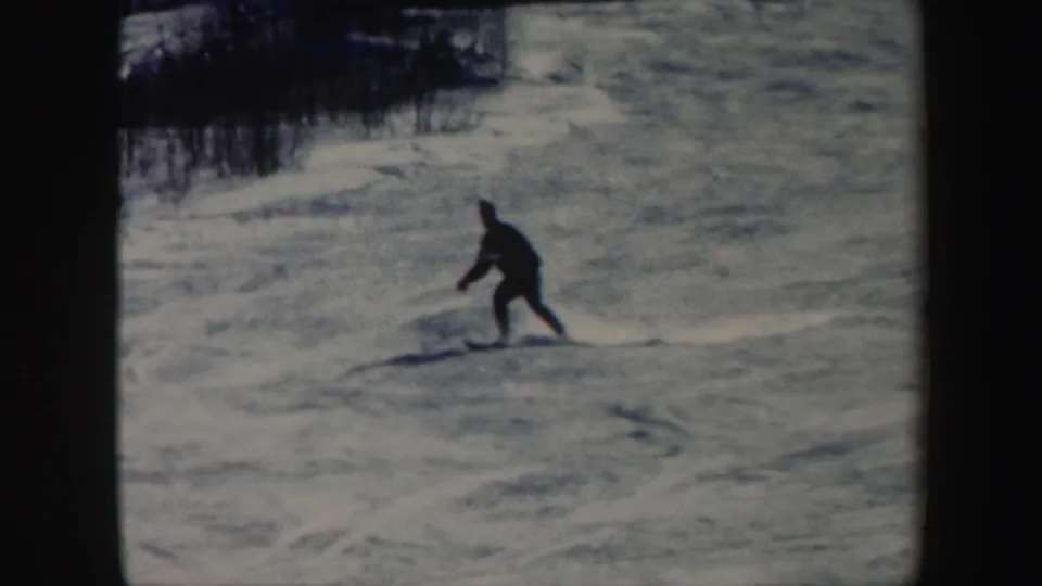 1962 Vermont home-movie still showing a skier closer to camera while moving across packed snow.