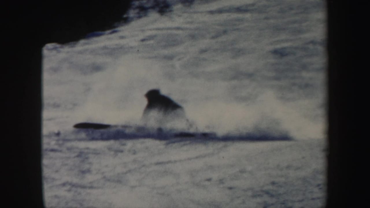 The skier has lost balance and is falling through snow on the Vermont hillside, with powder spraying behind.