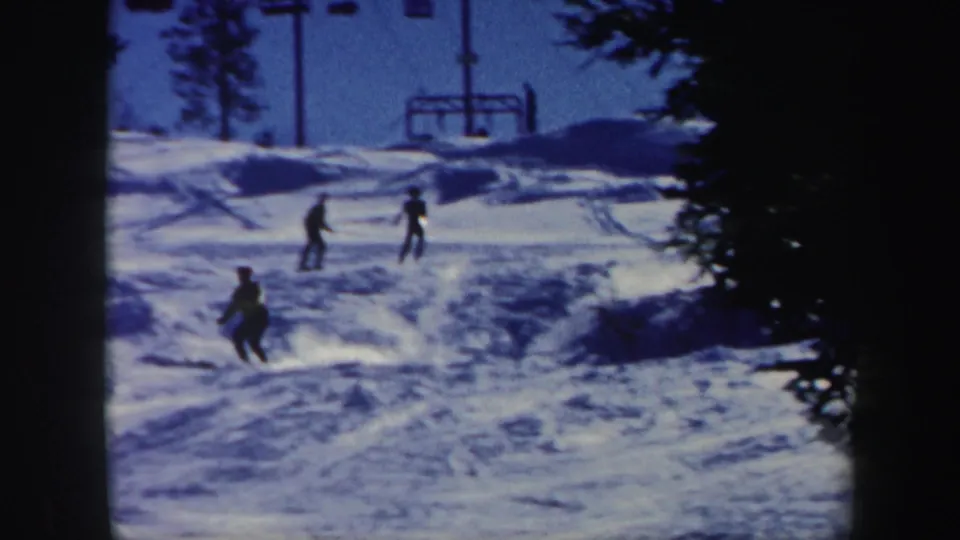1962 Vermont home-movie frame showing multiple skiers descending a snowy resort slope near the ski lift.