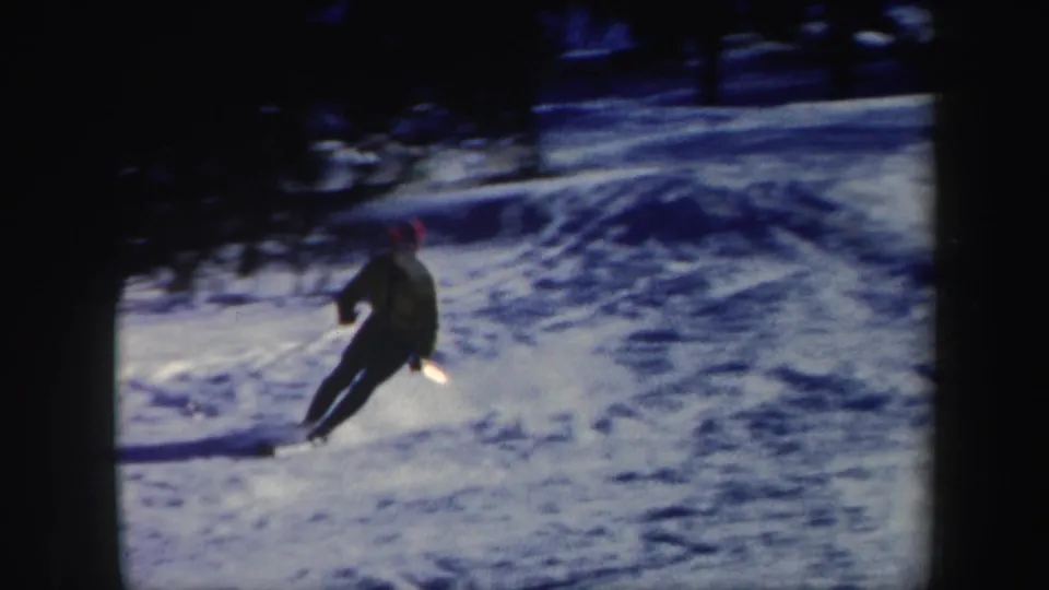 A skier in a yellow sweater and red hat turns across a snowy Vermont slope in 1962 home-movie footage.