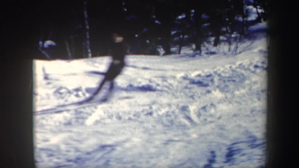 A skier enters the edge of a snowy Vermont slope in 1962 home-movie footage, with evergreen trees in the background.
