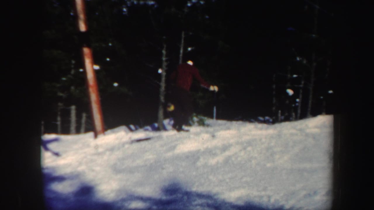 1962 Vermont frame with a skier near the edge of a snow-covered slope bordered by dark forest.