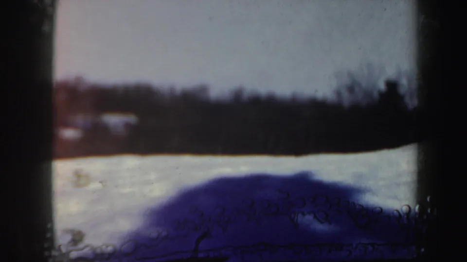 1962 Vermont winter slope seen in soft 8mm color, with snow in the foreground and bare trees along the horizon.