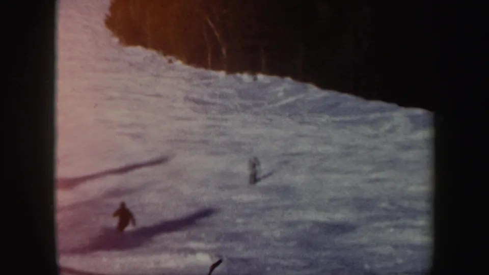 A wide 1962 Vermont ski-slope view shows small figures crossing the snow below a dark wooded edge.