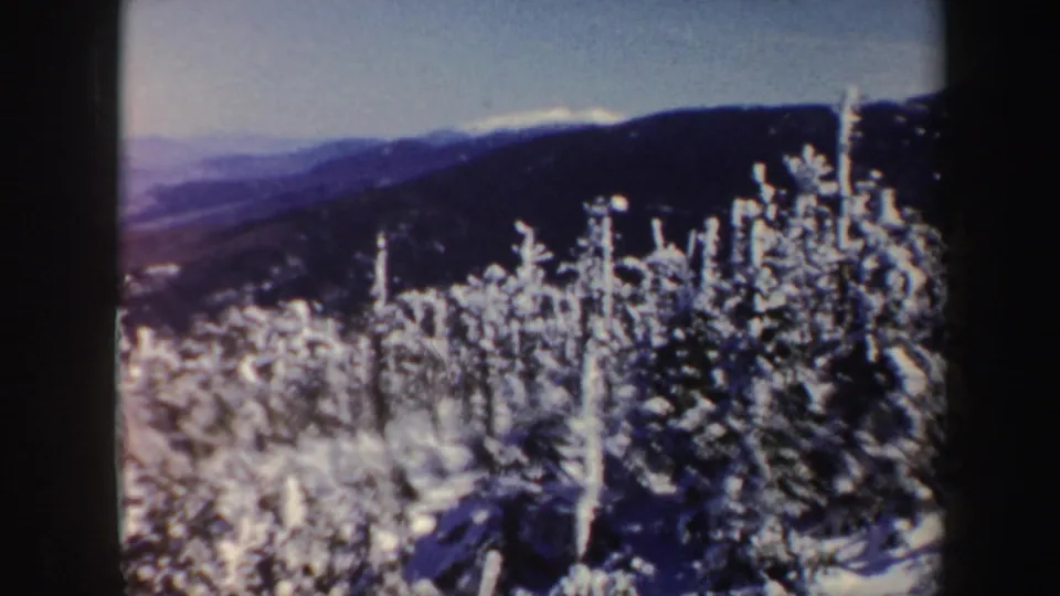 Frosted evergreens stand in the foreground with Vermont ridgelines and distant mountains in soft 1962 8mm color.