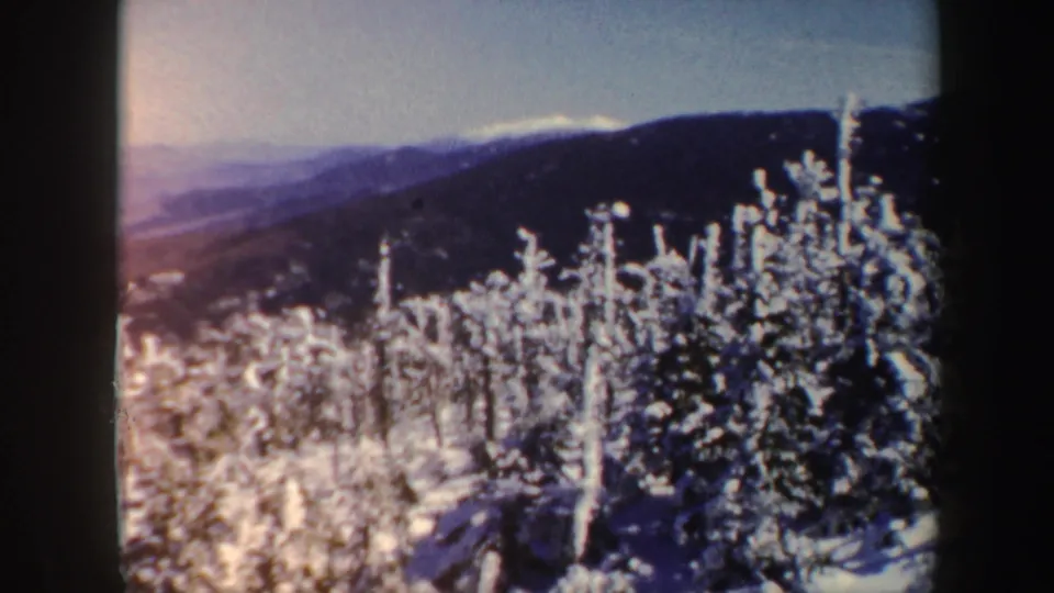 A Vermont mountainside view shows frosted trees, layered hills, and soft winter haze in 1962 home-movie footage.