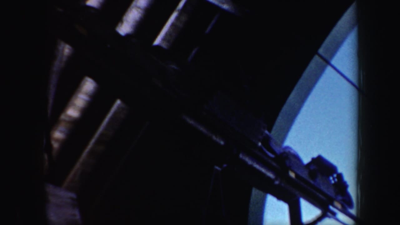 Dark close-up of ski lift machinery with metal arms and blue background.