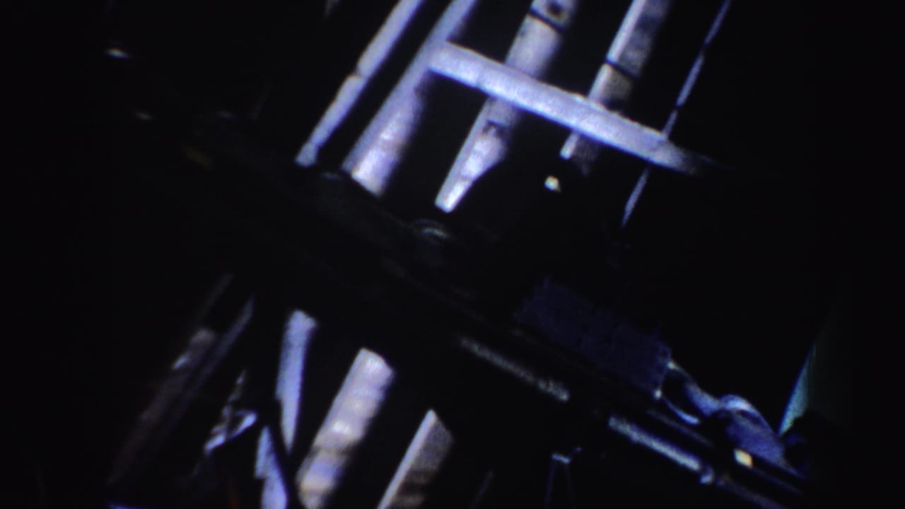 1962 Vermont home-movie frame showing dark ski lift structure with pale metal bars and cable components.