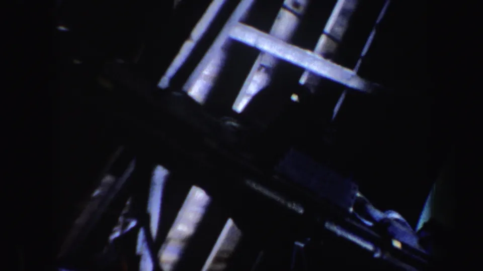 1962 Vermont home-movie frame showing dark ski lift structure with pale metal bars and cable components.