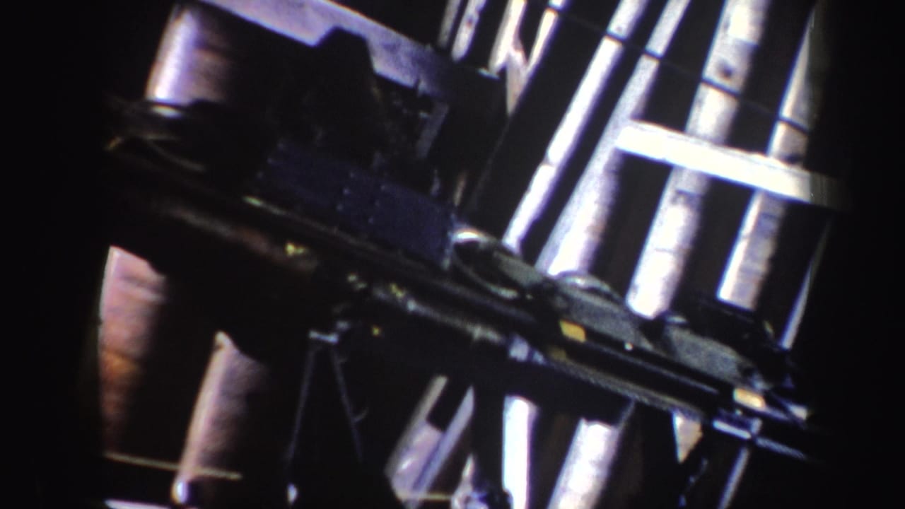 Angled close-up of metal ski-area equipment in vintage 8mm footage, with strong contrast and partial framing.