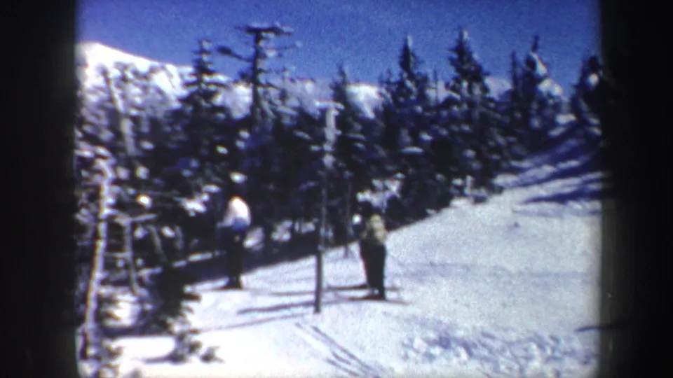 Three distant people move through snow in Vermont, 1962, with evergreens, a mountain slope, and bright winter light visible.