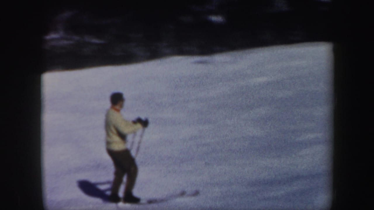 Adult skier gliding downhill across bright snow.