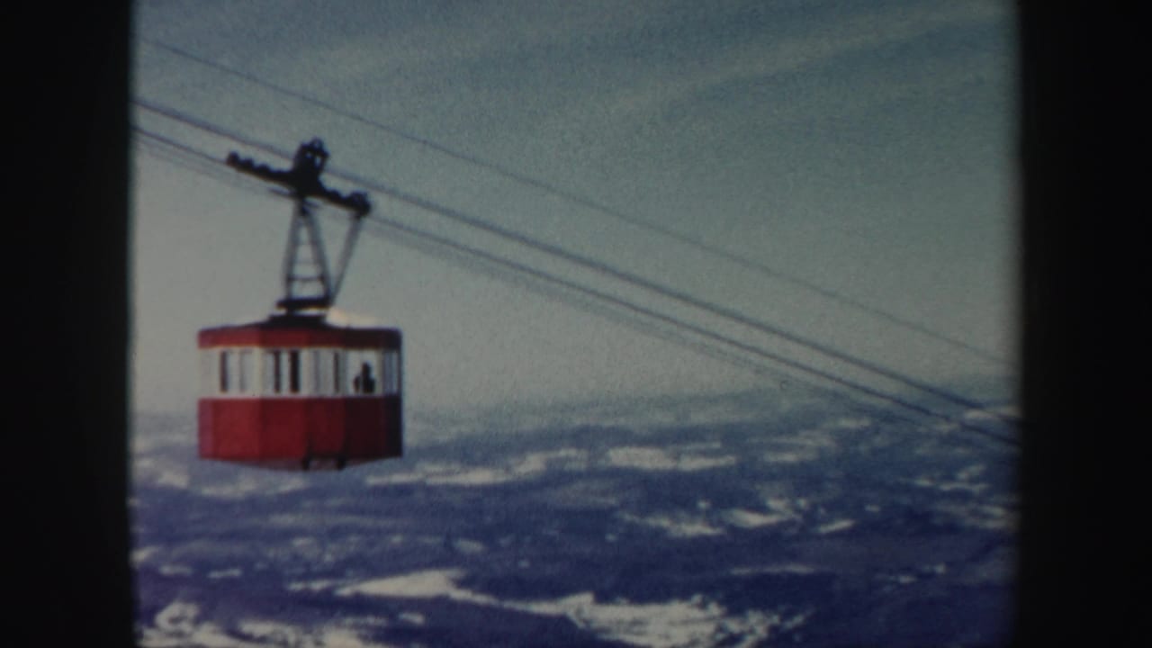 Red gondola car gliding across cables over a broad Vermont mountain view in vintage 8mm footage from 1962.