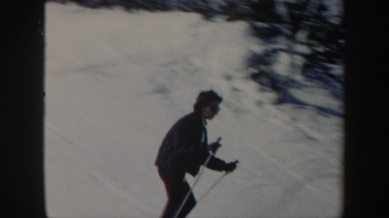 Woman skier in dark clothing uses poles while moving across a snowy Vermont slope in 1962 home-movie footage.