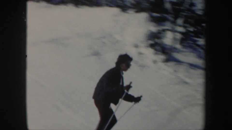 Woman skier in dark clothing uses poles while moving across a snowy Vermont slope in 1962 home-movie footage.
