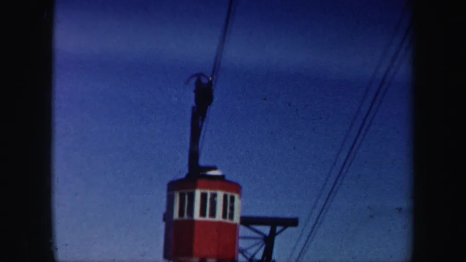 A red-and-white ski lift car appears beneath overhead cables in the same 1962 Vermont winter home movie.