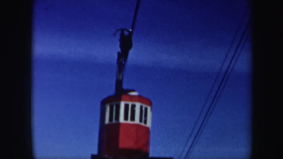 A closer home-movie view shows the red ski lift car and cable lines against a clear blue Vermont sky.