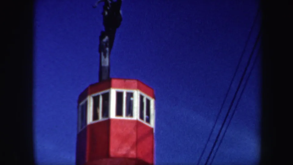 1962 Vermont 8mm still with the red ski-lift cabin closer to the camera, set against blue sky and diagonal lift lines.