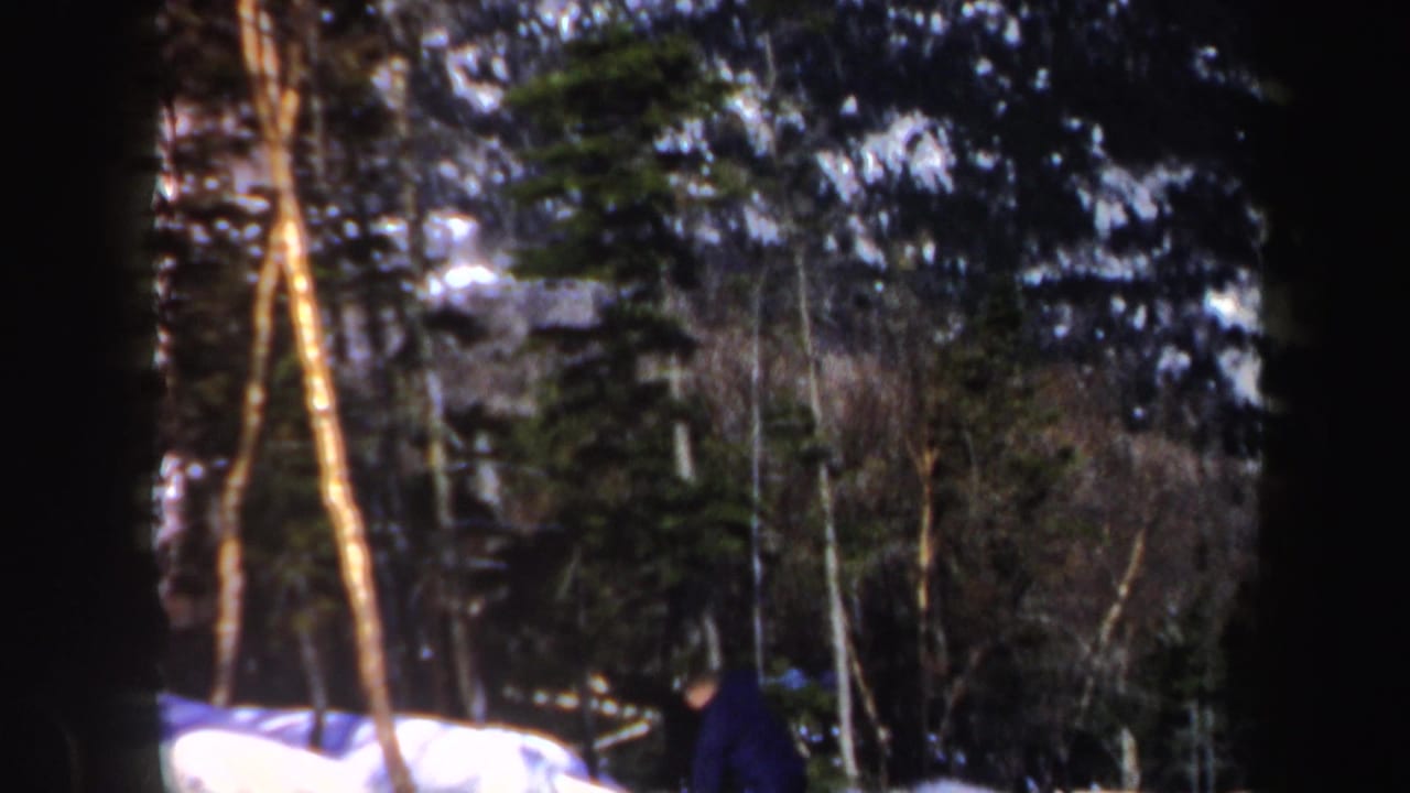 Distant skier continues downhill through trees on a snowy Vermont mountain slope in 1962 8mm footage.