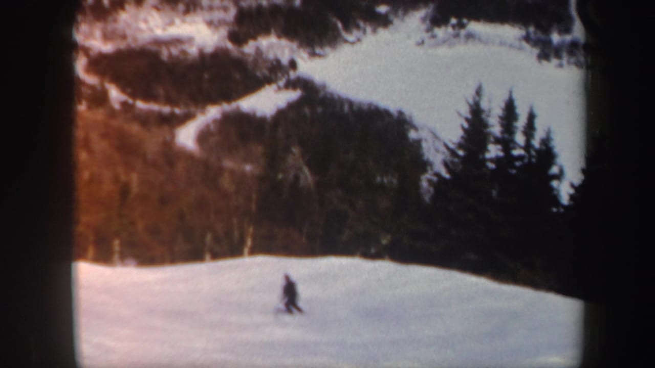 The skier appears farther across the Vermont snow slope, framed by dark trees and warm 8mm color.