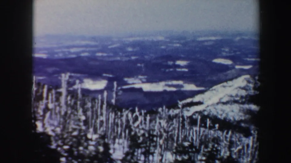 1962 Vermont 8mm frame opening to a wider snowy valley view with trees, hills, and patchy fields.