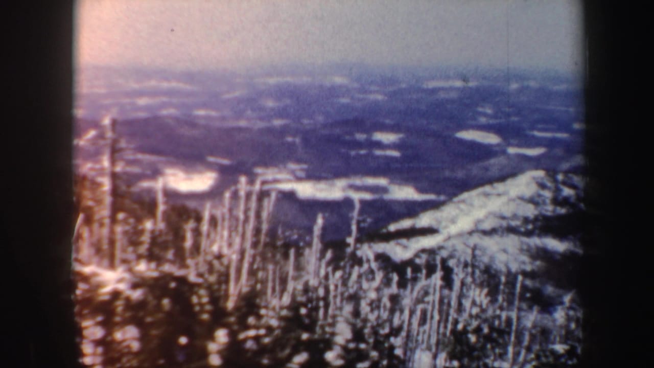 1962 Vermont home-movie view of a snowy mountain ridge, bare winter trees, distant valley, and pale sky.