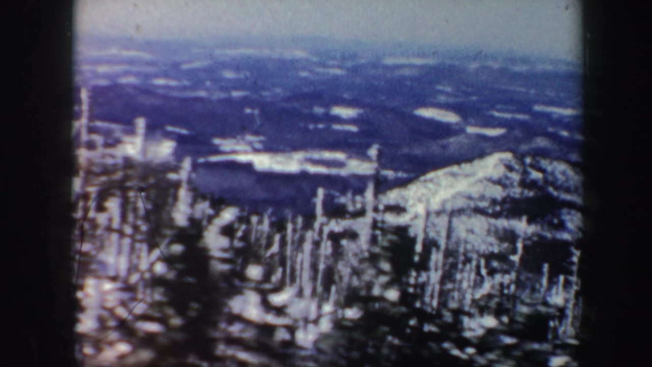 A cool-toned 1962 Vermont mountain vista shows snow on the slope, distant terrain, and dark film-frame edges.
