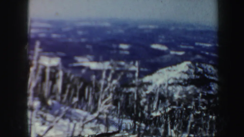 Vermont 8mm footage shows snow-coated trees and a mountain slope dropping toward a distant winter valley.