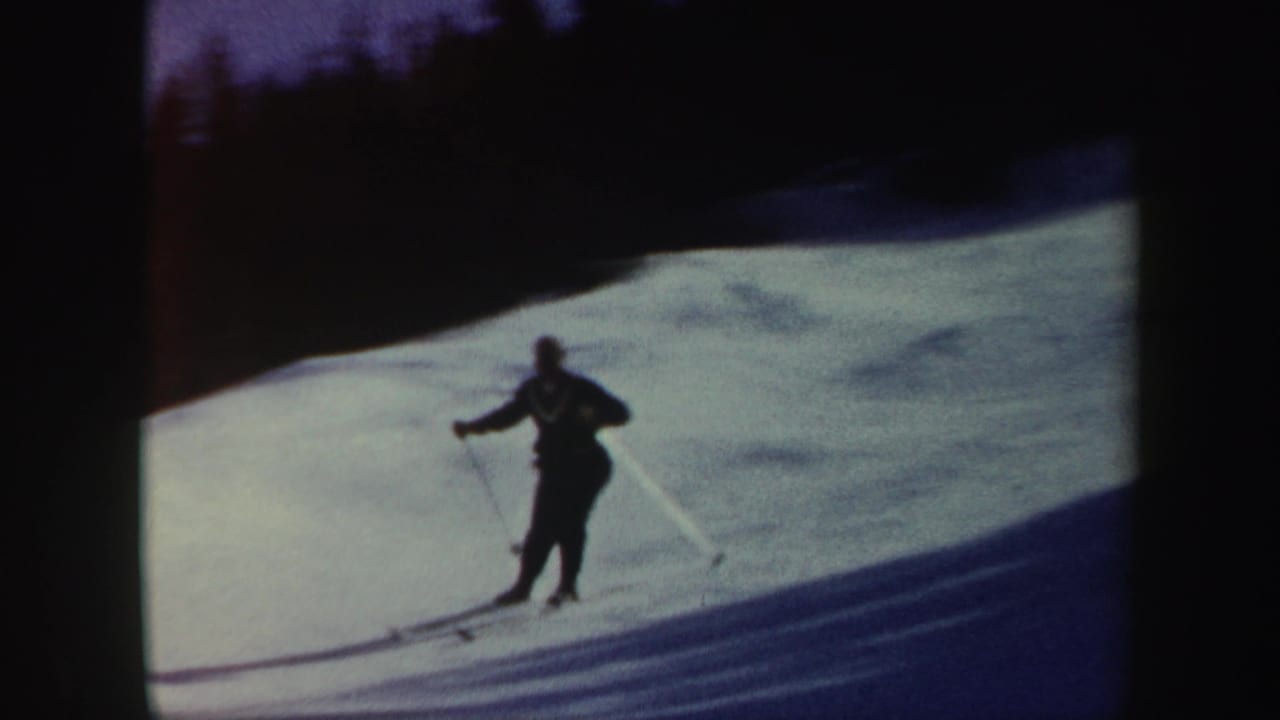 1962 Vermont 8mm frame of a skier moving across a bright snowy slope, partly silhouetted by exposure.