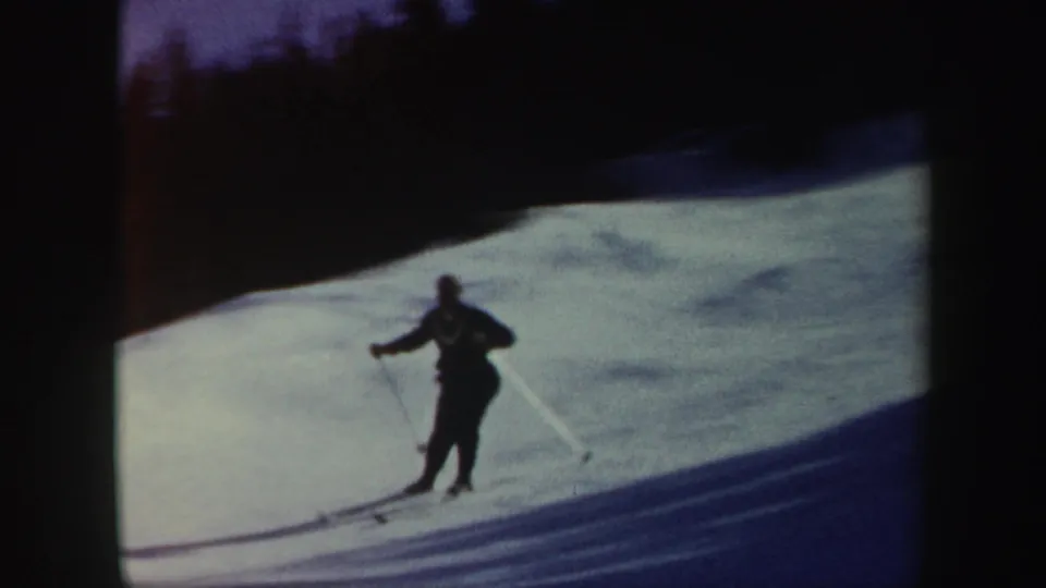 1962 Vermont 8mm frame of a skier moving across a bright snowy slope, partly silhouetted by exposure.