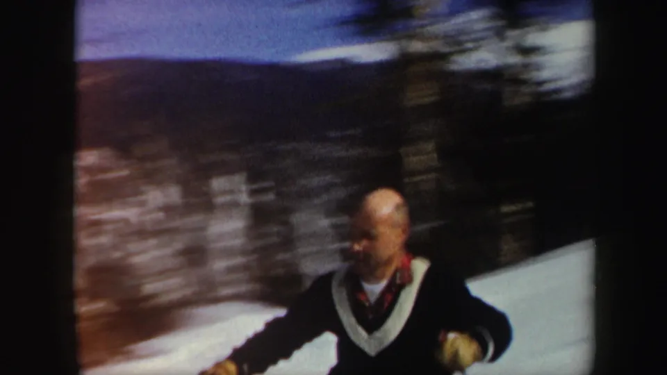 1962 Vermont 8mm frame with a closer view of a middle-aged skier in a dark sweater with a white V-neck collar.