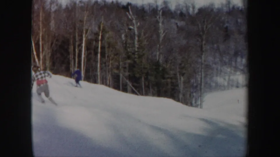 Two skiers share the frame on a 1962 Vermont slope, one closer in patterned clothing and one farther downhill in blue.