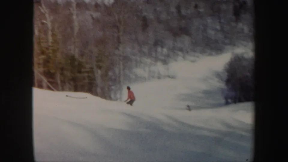 Adult skier in a red jacket moves down a snow-covered Vermont slope in 1962 home-movie footage.