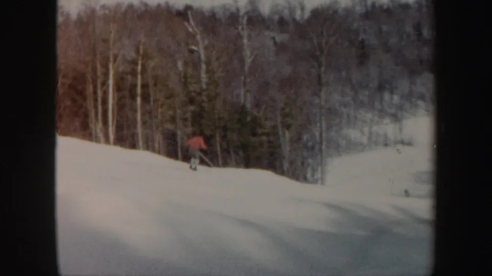The skier in red passes near trees along a snow-covered Vermont ski slope in 1962 footage.