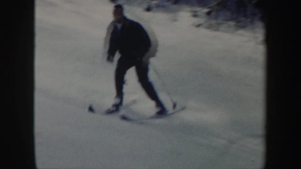 An adult male skier in dark clothing approaches the camera during a turn on a Vermont snowy slope.