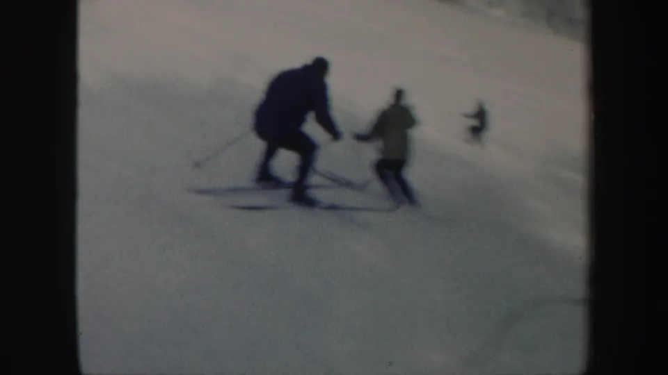 Two skiers descend a snowy Vermont slope, with a distant skier visible farther uphill in the 1962 8mm frame.