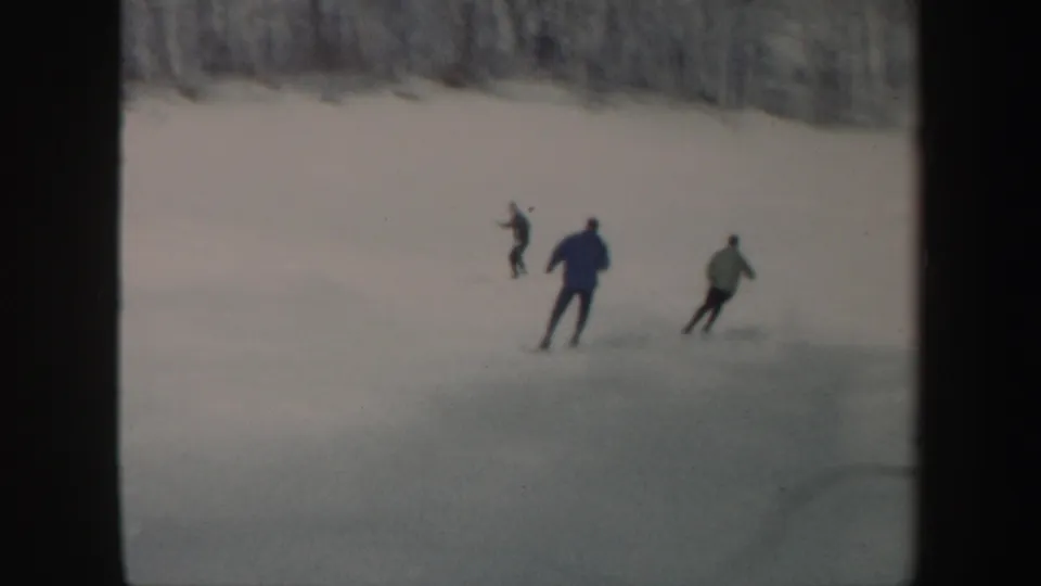 Three skiers move across a broad snowy Vermont slope in a softly focused 1962 8mm home-movie frame.