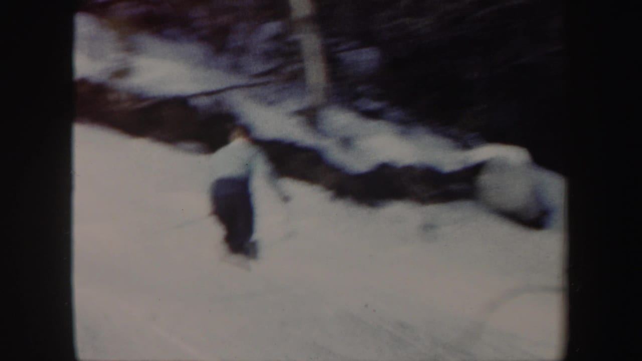 Skier continues downhill near snow-covered rocks.