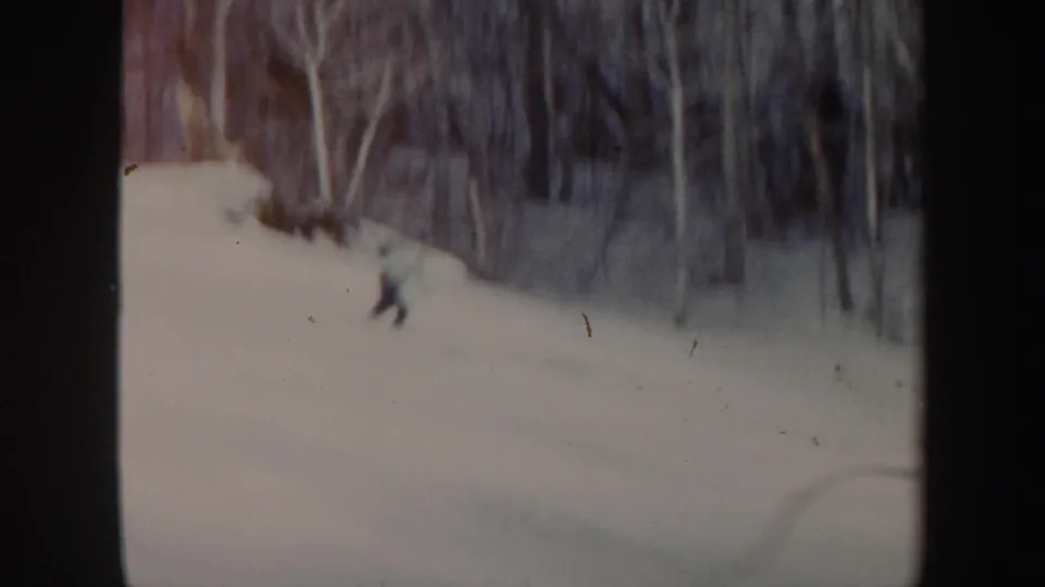 The skier moves downhill across a pale snowy Vermont slope, framed by winter woods and 8mm film borders.