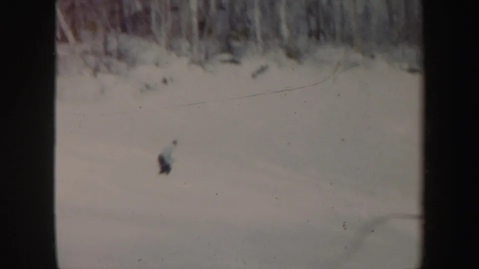 A small figure skis across the lower part of a broad snowy hill in this Vermont home-movie frame.